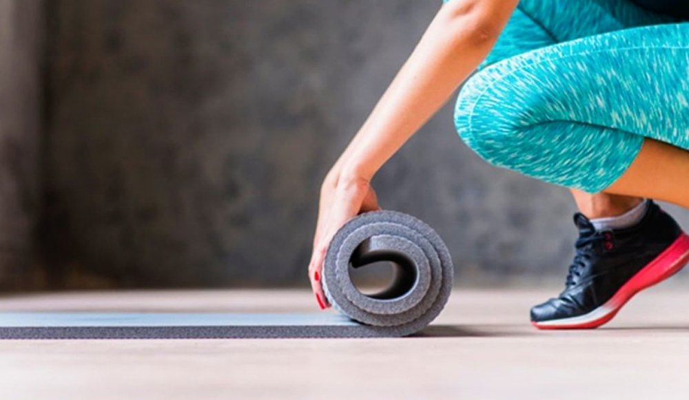 The 5 Fitness Products That Will Help You Get in Shape from Home in 2025 5 a person rolling a yoga mat